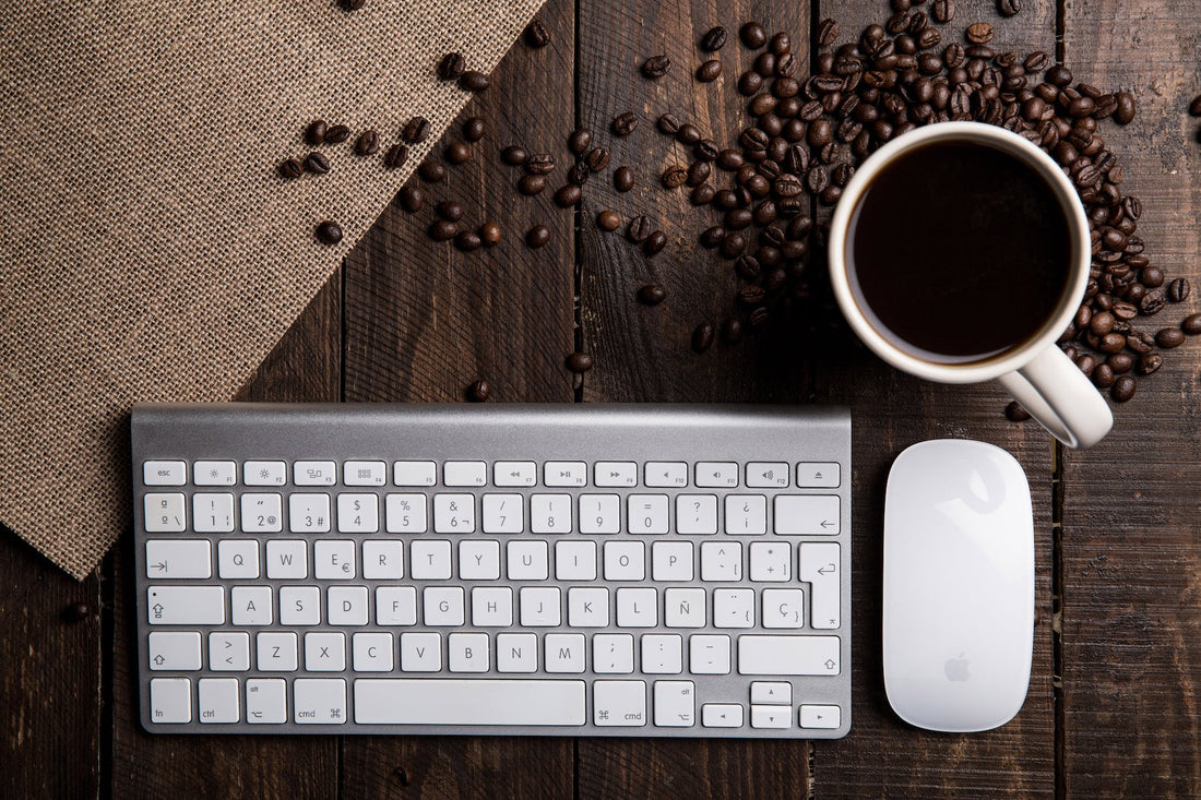 Laptop, coffee mug, and notebook on a wooden desk workspace.