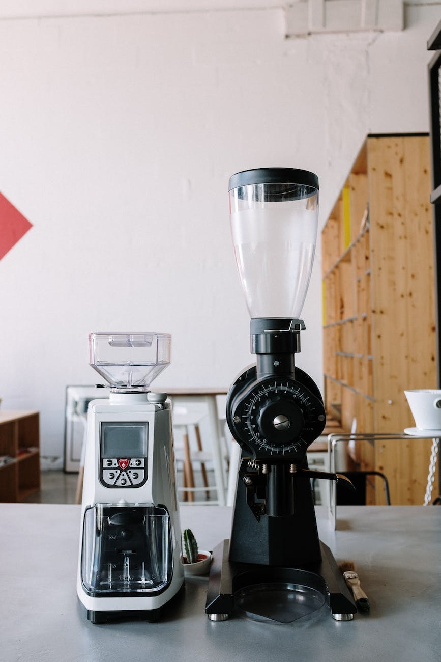 High-quality burr coffee grinder beside freshly ground beans on a kitchen counter.